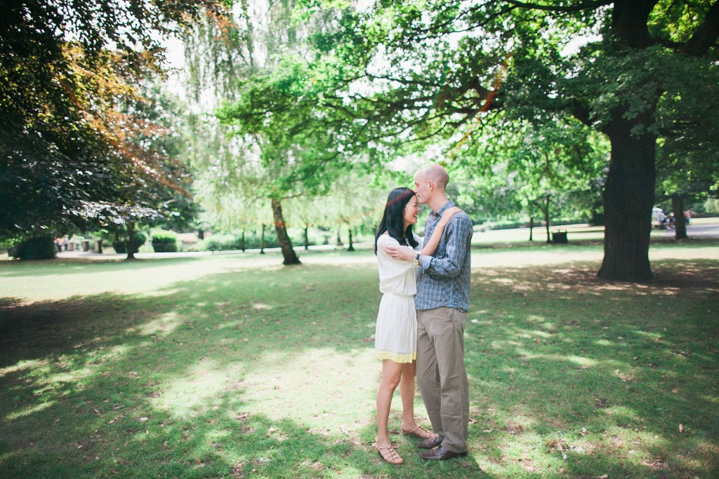 nicholas-lau-nicholau-weddings-london-film-photography-beautiful-pretty-engagement-love-interracial-kiss-on-the-forehead-lens-glare-tree-canopy-embrace