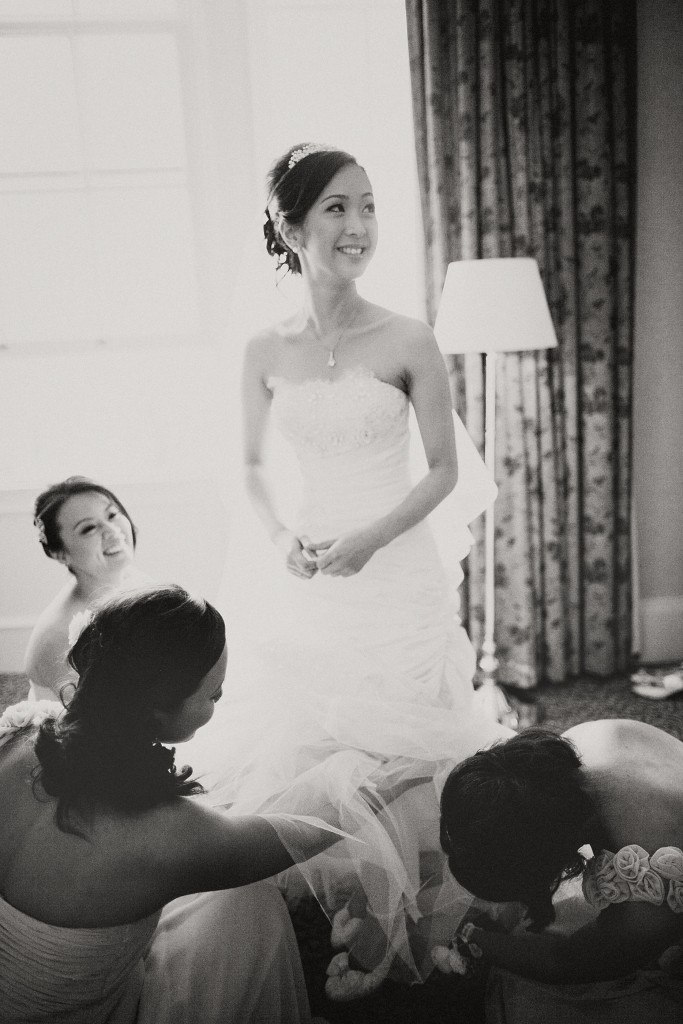 nicholas-lau-nicholau-london-film-photography-chinese-asian-wedding-black-and-white-bridesmaids-putting-shoes-on-for-bride