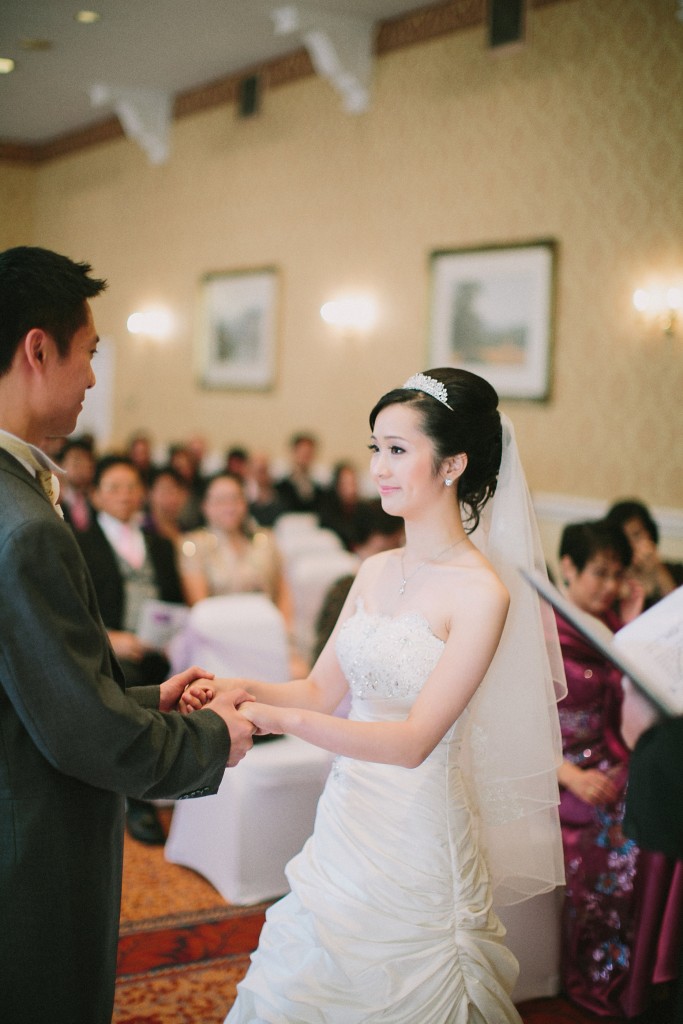nicholas-lau-nicholau-london-film-photography-chinese-asian-wedding-bride-holds-her-husbands-hands-during-vows-veil-smiling-ballgown
