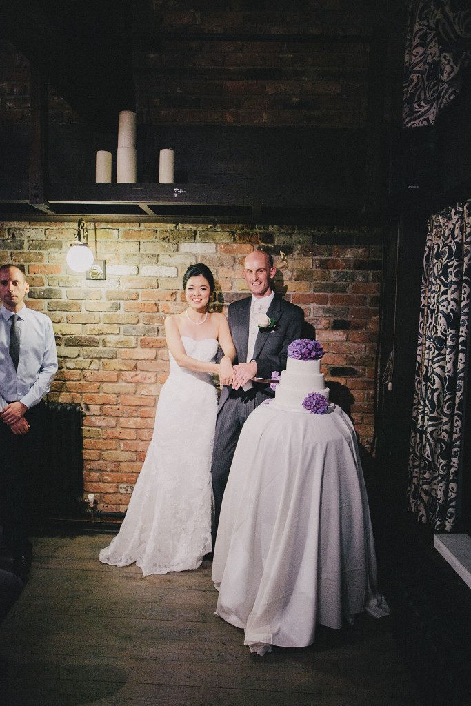 nicholau-nicholas-lau-interracial-wedding-reception-cut-the-cake-three-tiered-cake-purple-and-white-urban-bricks