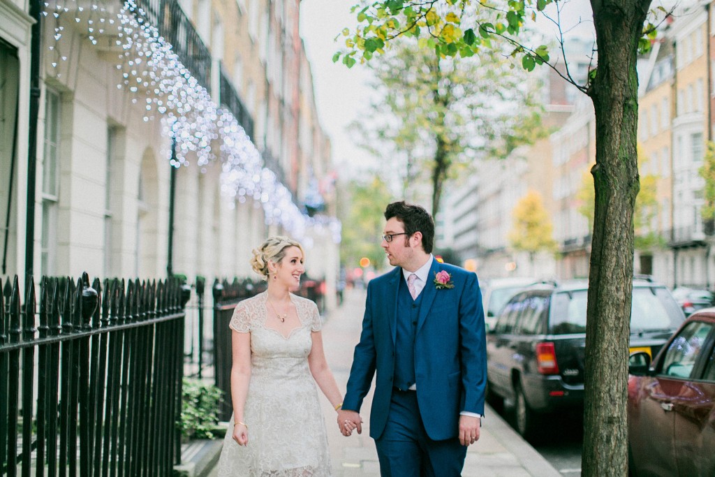 nicholas-lau-nicholau-wedding-photography-photographer-fine-art-film-winter-christmas-london-UK-modern-unique-the-arch-asia-house-holding-hands-sidewalk-blue-suit-white-dress-knee-length